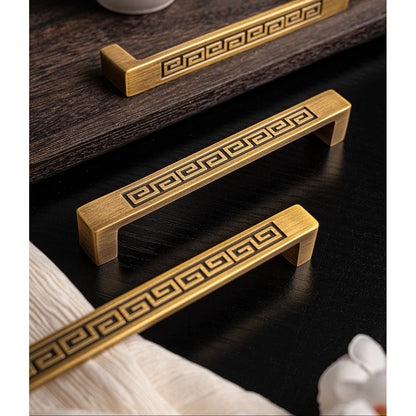 Gouden ladegrepen met Grieks sleutelpatroon op zwarte houten achtergrond, luxe interieuraccessoire
